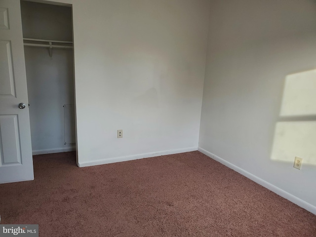 unfurnished bedroom with a closet and dark carpet