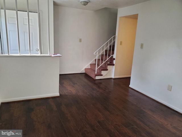 unfurnished room with a textured ceiling and dark hardwood / wood-style flooring