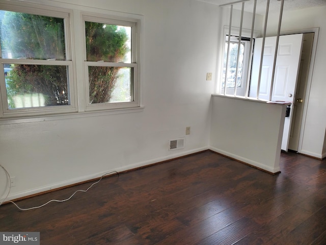 spare room featuring dark hardwood / wood-style flooring and plenty of natural light