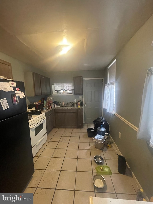 kitchen featuring black refrigerator, light tile patterned floors, and gas range gas stove