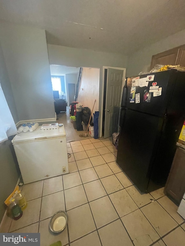 kitchen with black refrigerator and light tile patterned flooring