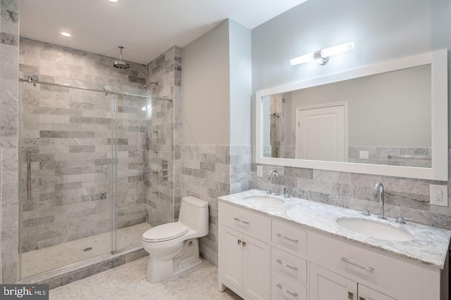 bathroom featuring double vanity, a stall shower, a sink, and tile walls