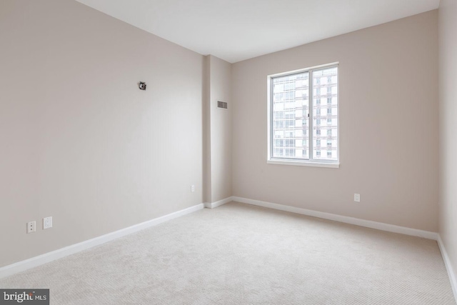 empty room with light colored carpet, visible vents, and baseboards