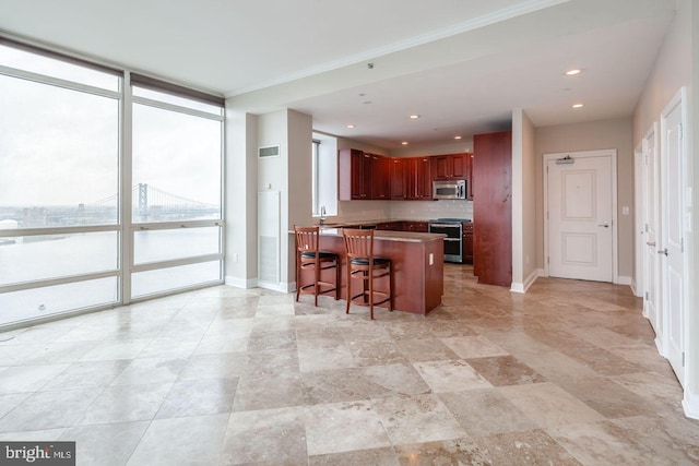 kitchen with a kitchen bar, appliances with stainless steel finishes, kitchen peninsula, expansive windows, and sink