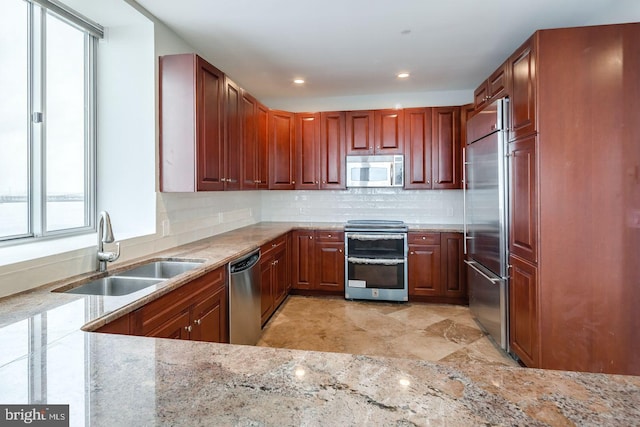 kitchen with light stone counters, sink, appliances with stainless steel finishes, and tasteful backsplash