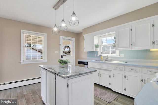 kitchen with tasteful backsplash, white cabinets, a kitchen island, baseboard heating, and a sink