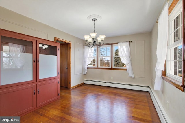 unfurnished dining area with baseboards, a chandelier, baseboard heating, and wood finished floors