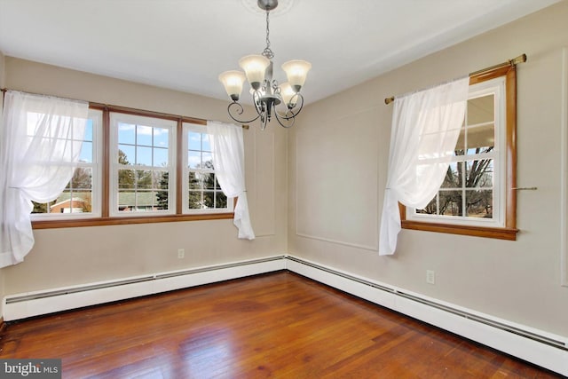 spare room with a baseboard heating unit, a notable chandelier, and wood finished floors