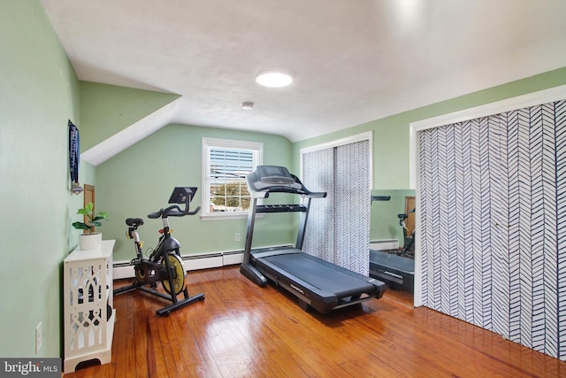 workout area featuring a baseboard heating unit, vaulted ceiling, and hardwood / wood-style flooring