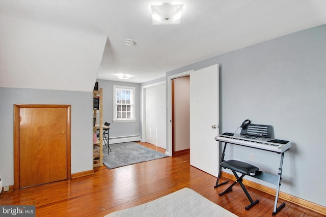 office area with a baseboard radiator, baseboards, and wood finished floors