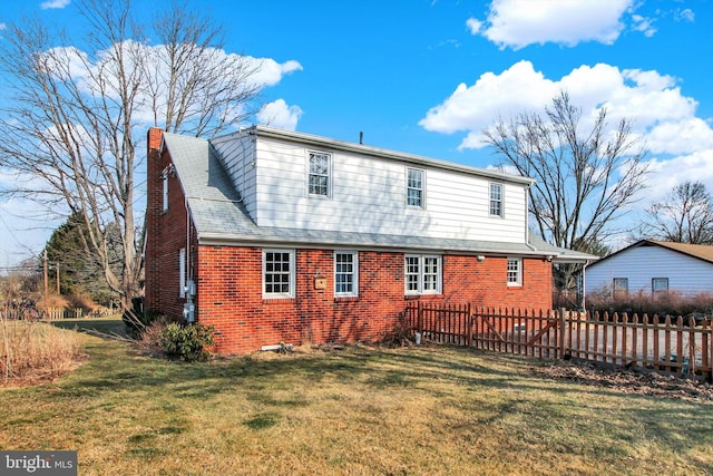 back of house with a yard, a chimney, fence, and brick siding