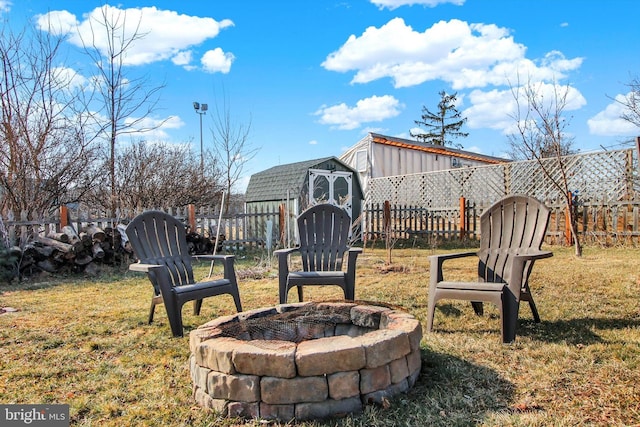 view of yard featuring a shed, fence, a fire pit, and an outbuilding