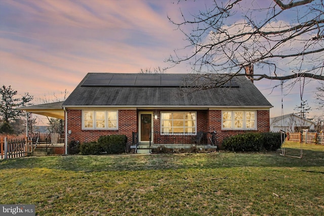 view of front of home with brick siding, fence, and a yard