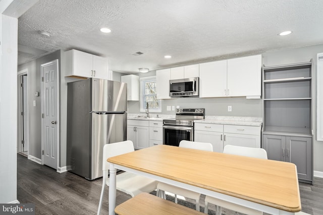 kitchen featuring sink, dark hardwood / wood-style floors, a textured ceiling, white cabinetry, and stainless steel appliances