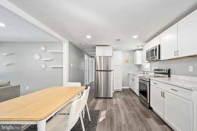 kitchen with white cabinetry, sink, stainless steel appliances, and a textured ceiling