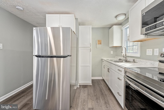 kitchen with white cabinets, appliances with stainless steel finishes, light hardwood / wood-style flooring, and sink