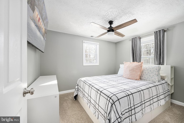 carpeted bedroom with ceiling fan, a textured ceiling, and multiple windows