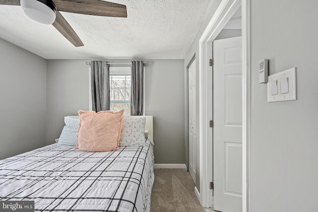 bedroom with ceiling fan, carpet floors, and a textured ceiling