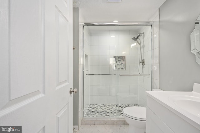 bathroom with tile patterned floors, toilet, vanity, and walk in shower