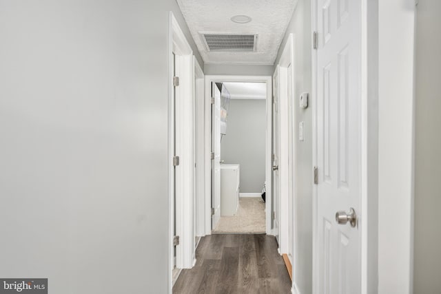 hallway featuring a textured ceiling and dark hardwood / wood-style floors