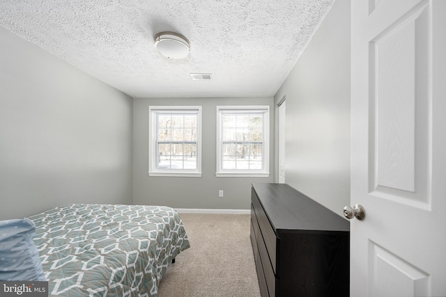 bedroom featuring light carpet and a textured ceiling