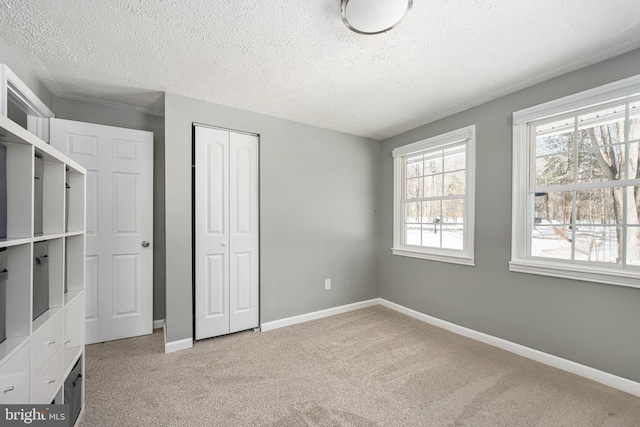 unfurnished bedroom with light carpet, a textured ceiling, and a closet