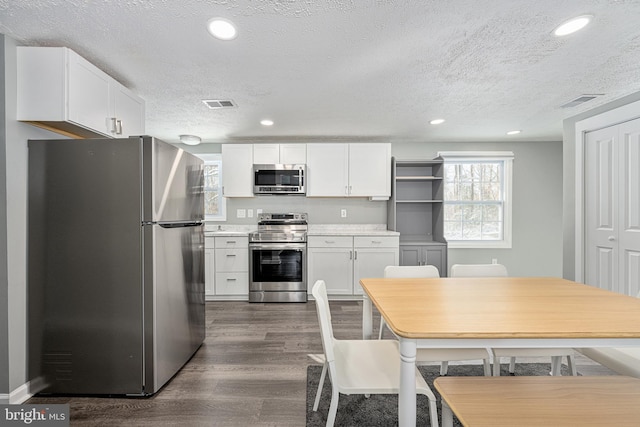 kitchen with white cabinets, dark hardwood / wood-style flooring, a textured ceiling, and appliances with stainless steel finishes