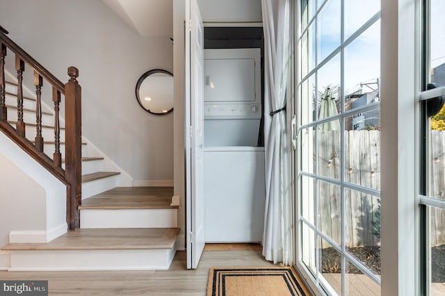 stairs with hardwood / wood-style flooring, plenty of natural light, and stacked washer / dryer