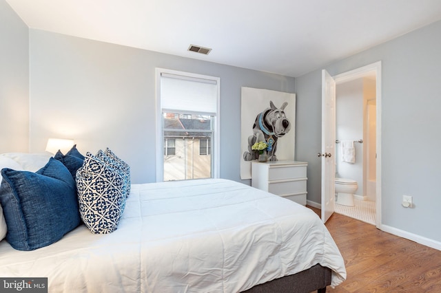 bedroom featuring connected bathroom and hardwood / wood-style floors