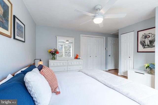 bedroom featuring wood-type flooring, two closets, and ceiling fan