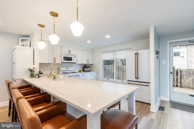 kitchen featuring pendant lighting, white appliances, sink, kitchen peninsula, and white cabinetry