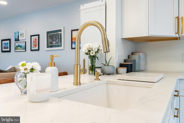 details with light stone countertops, white cabinetry, and sink