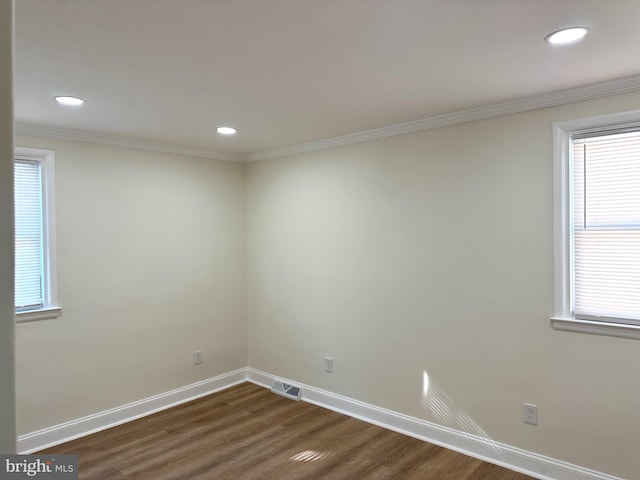 empty room with dark hardwood / wood-style flooring, a wealth of natural light, and crown molding