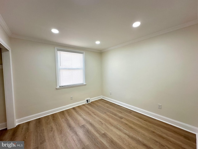 empty room with wood-type flooring and crown molding