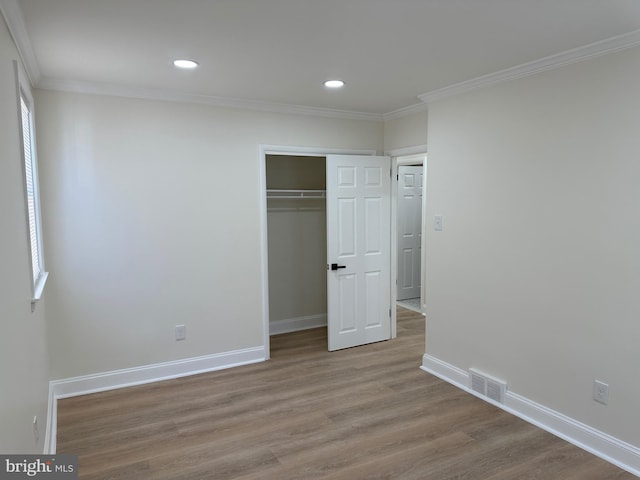 unfurnished bedroom with light hardwood / wood-style floors, multiple windows, crown molding, and a closet