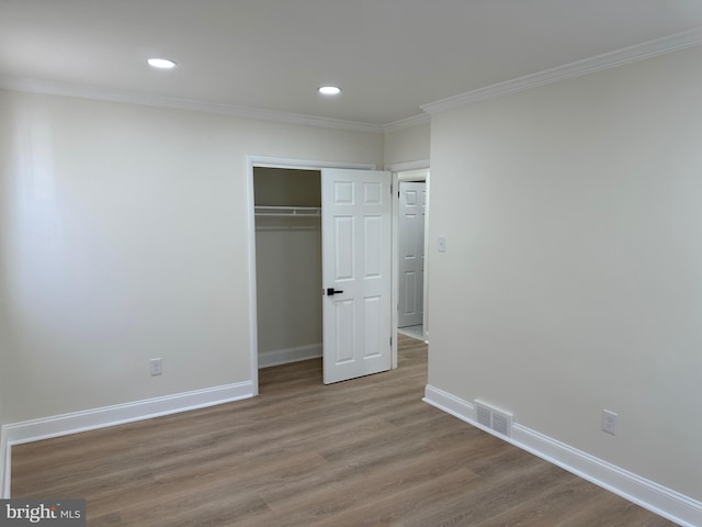 unfurnished bedroom with hardwood / wood-style flooring, a closet, and crown molding