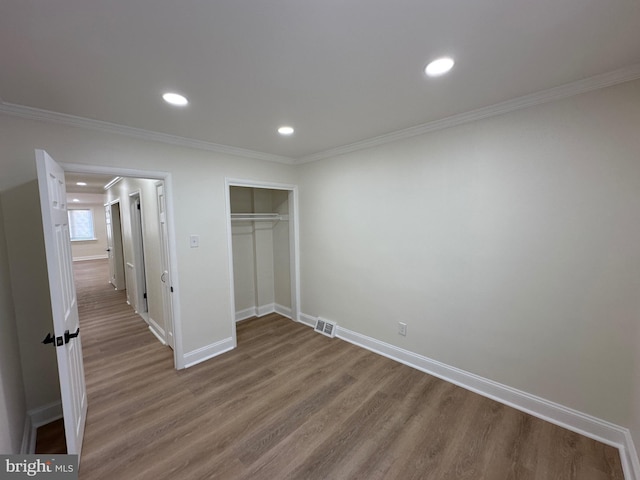 unfurnished bedroom featuring crown molding, a closet, and hardwood / wood-style flooring