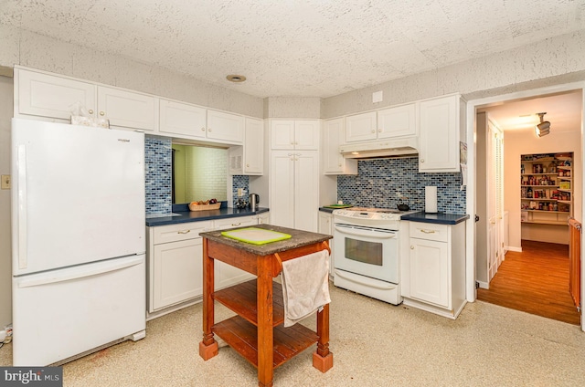 kitchen with white appliances, decorative backsplash, and white cabinets