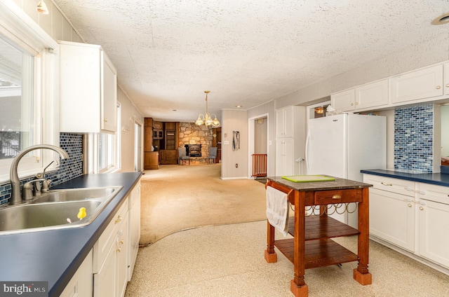 kitchen with white refrigerator, sink, light carpet, and white cabinets