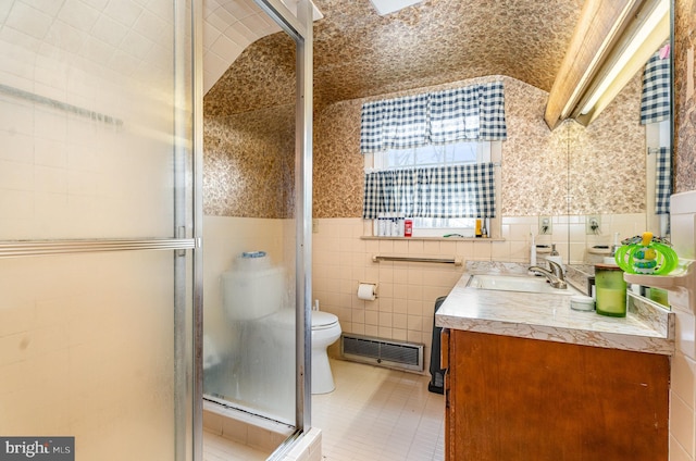 bathroom with a shower with shower door, tile walls, vanity, toilet, and tile patterned floors