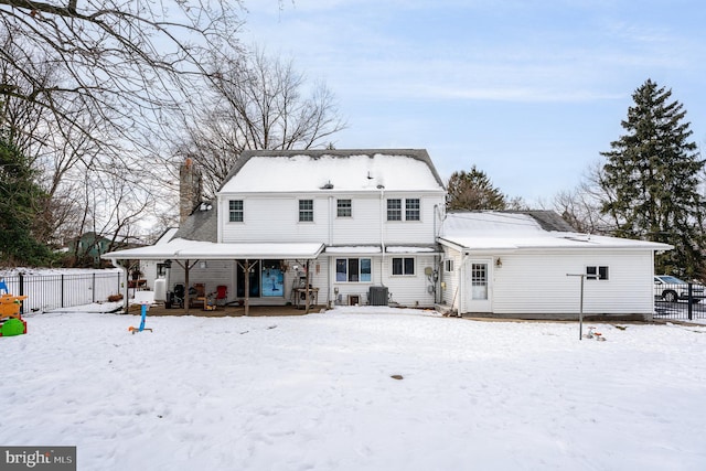 snow covered house featuring a porch and central air condition unit