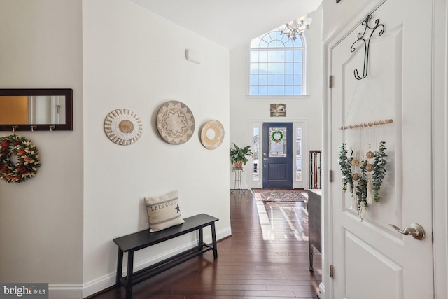 entryway with high vaulted ceiling, dark hardwood / wood-style floors, a wealth of natural light, and an inviting chandelier