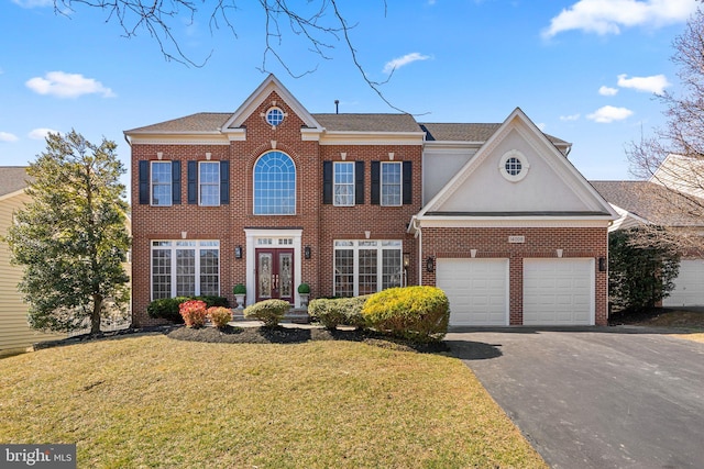 view of front facade with french doors, brick siding, an attached garage, and driveway