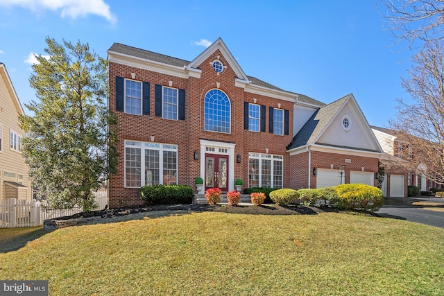 view of front of property featuring brick siding, an attached garage, fence, a front yard, and driveway