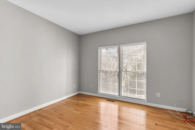 unfurnished room featuring visible vents, baseboards, and light wood finished floors