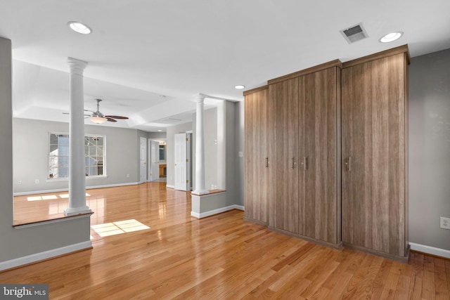 unfurnished living room with baseboards, light wood-style flooring, and ornate columns