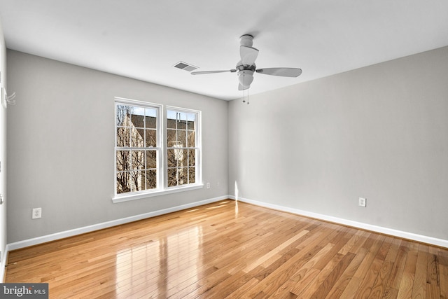 spare room with visible vents, a ceiling fan, baseboards, and hardwood / wood-style flooring