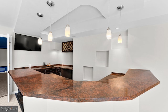 kitchen featuring hanging light fixtures, dark countertops, carpet floors, and a sink