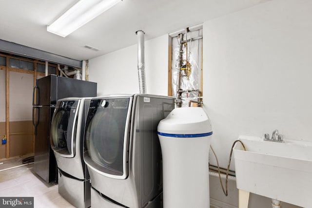 clothes washing area with light tile patterned floors, visible vents, independent washer and dryer, and a sink