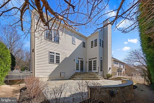 back of house with a patio area, entry steps, a chimney, and fence